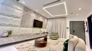 Una sala de estar moderna con pared de piedra, un televisor de pantalla plana, una mesa redonda de centro y un sofá.