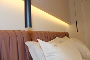 Un lit avec une tête de lit, des oreillers et un luminaire fixé au mur.