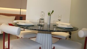 A modern dining area with a glass table, white upholstered chairs, and a vase with flowers. - Mareé Boutique Stay - Pizzo VV (Pizzo)
