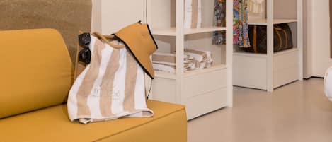 A modern interior with a yellow sofa, a white wardrobe, and a hanging light fixture.