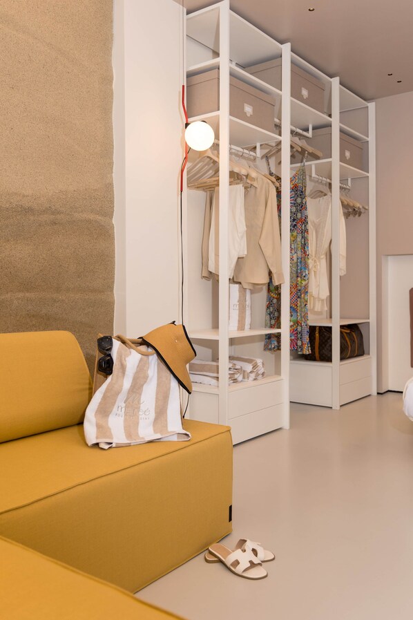 A modern interior with a yellow sofa, a white wardrobe, and a hanging light fixture.