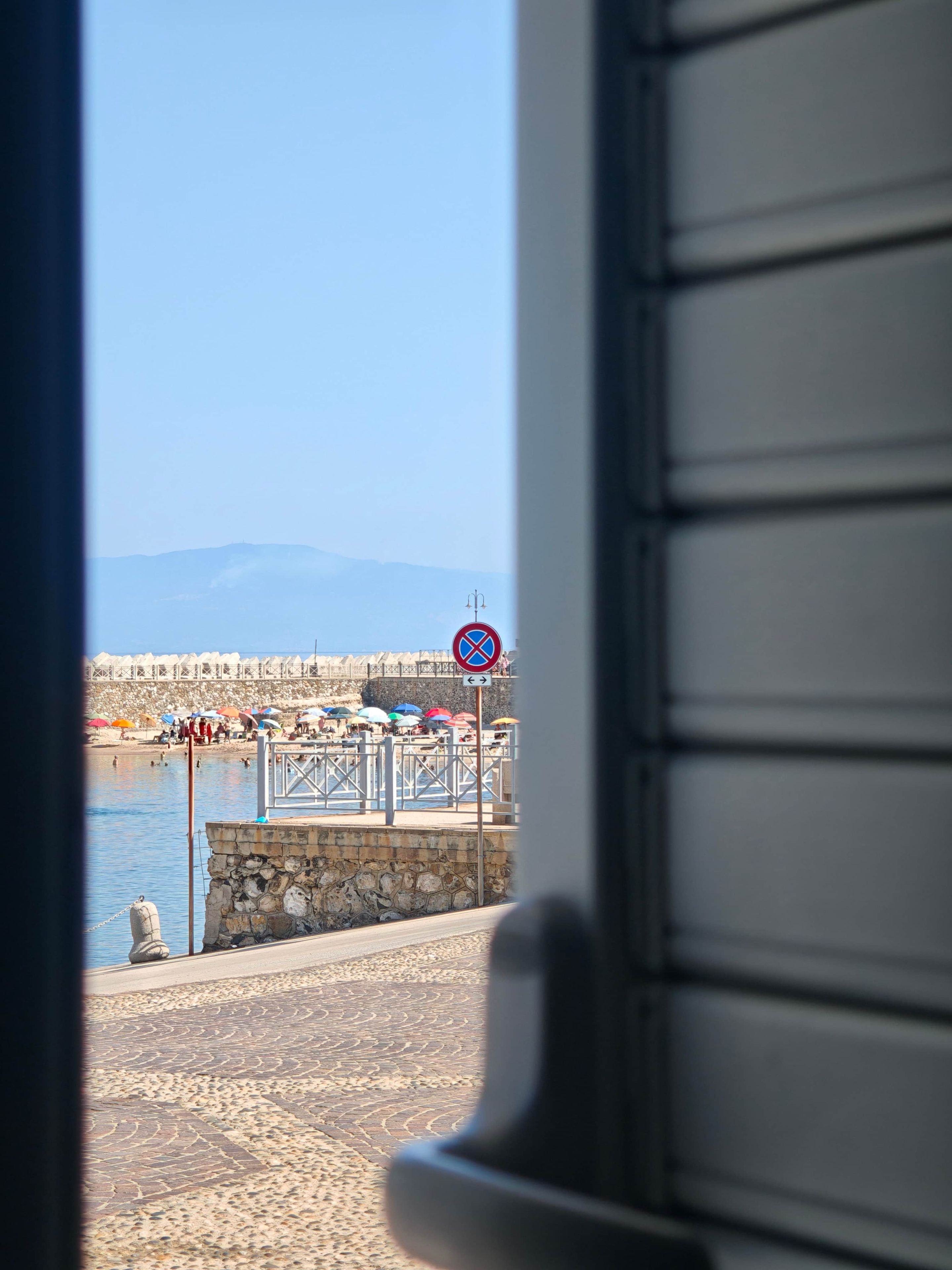 Une vue sur la côte, avec un ciel dégagé, un panneau indiquant qu’il est interdit de se garer et un mur de pierre.