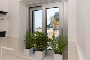 A bathroom with a window, white walls, and three potted plants.