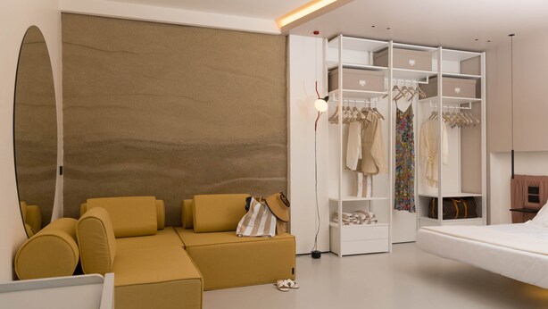 A modern bedroom with a sofa, a bed, a wardrobe, and a hanging light fixture. - Mareé Boutique Stay - Pizzo VV (Pizzo)