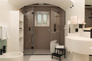 Une salle de bain moderne avec une douche à parois de verre, un lavabo blanc et un petit tabouret.