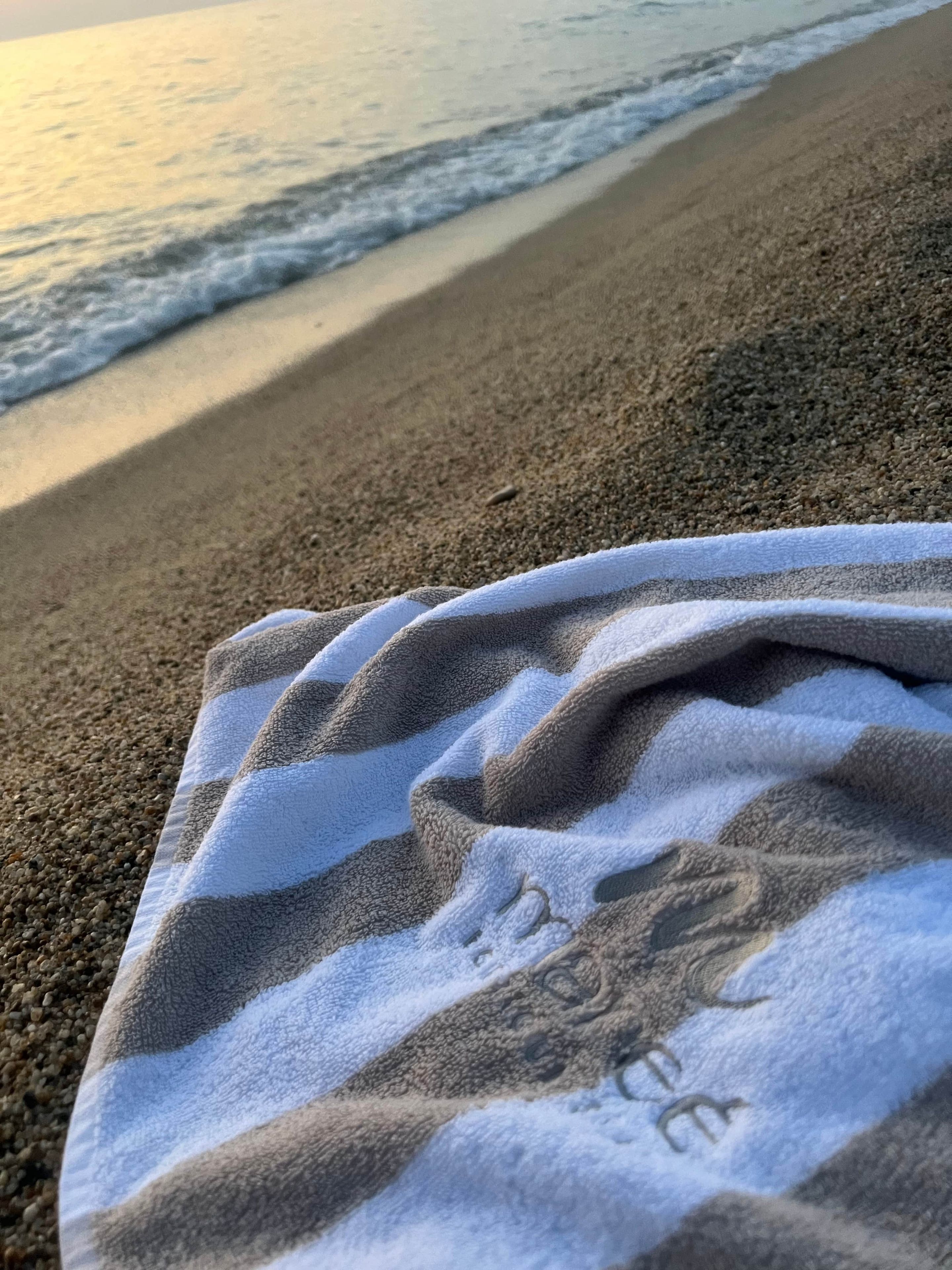 A beach towel on a sandy beach with waves in the background.