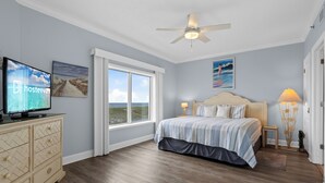 A bedroom with a bed, a television, a ceiling fan, and a large window. - Palm Beach D-21 (Orange Beach)