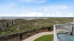 A beach view from a balcony with a wooden deck and a grassy area. - Palm Beach D-21 (Orange Beach)