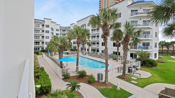 A multi-story hotel with a swimming pool surrounded by palm trees and lounge chairs. - Palm Beach D-21 (Orange Beach)