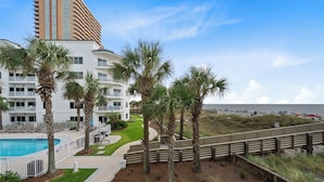 A beachfront hotel with a swimming pool, palm trees, and a beach view. - Palm Beach D-21 (Orange Beach)