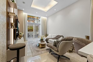 A modern living room with a sofa, armchairs, a coffee table, and a dining table. There is a sliding glass door leading to an outdoor area. - Palm Jumeirah 2BR w/ Direct Beach Access (Dubai)