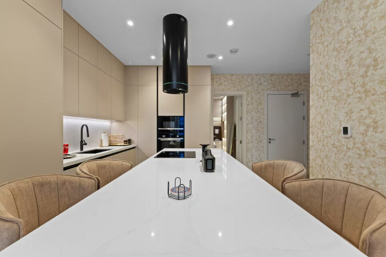 A modern kitchen with a central island, built-in appliances, and a pendant light.