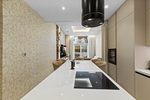 A modern kitchen with a central island, built-in appliances, and a large window providing natural light. - Palm Jumeirah 2BR w/ Direct Beach Access (Dubai)