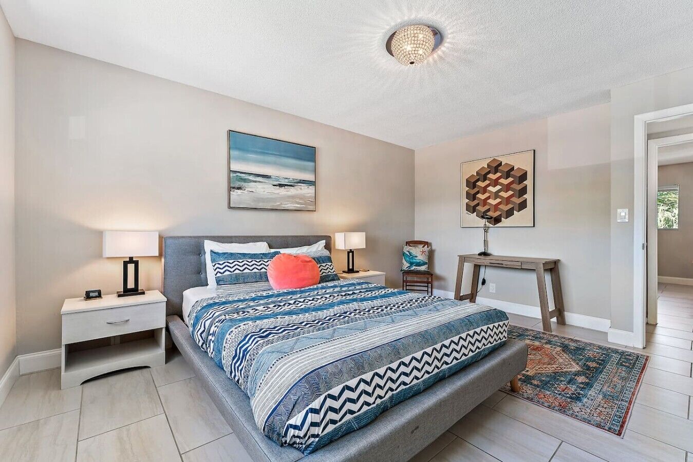 A bedroom with a bed, nightstands, a desk, and a rug.