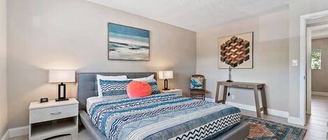 A bedroom with a bed, nightstands, a desk, and a rug.