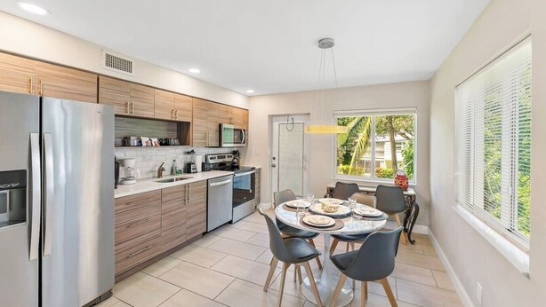 Een moderne keuken met roestvrijstalen apparatuur, houten kastjes en een eethoek met een tafel en stoelen.