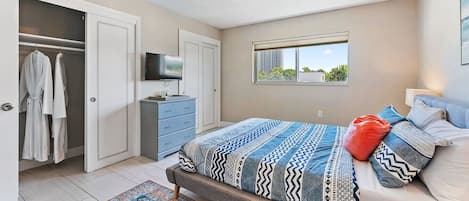 Un dormitorio con cama, televisión, armario y ventana.