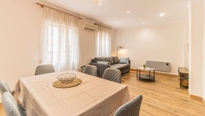 Ein modernes Wohnzimmer mit einer Couch, einem Esstisch mit Stühlen und einem Deckenventilator.