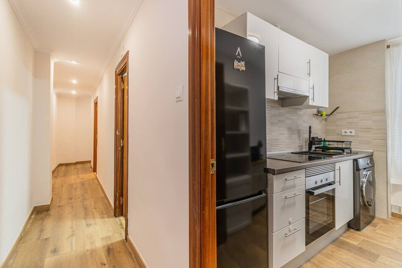 A modern kitchen with a refrigerator, oven, and sink.