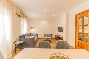 Un salon moderne comprenant un canapé, des fauteuils, une table à manger et un téléviseur.