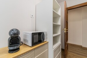 A kitchenette with a microwave, coffee maker, and storage shelves. - Explore Zaragoza from the City Center (Zaragoza)