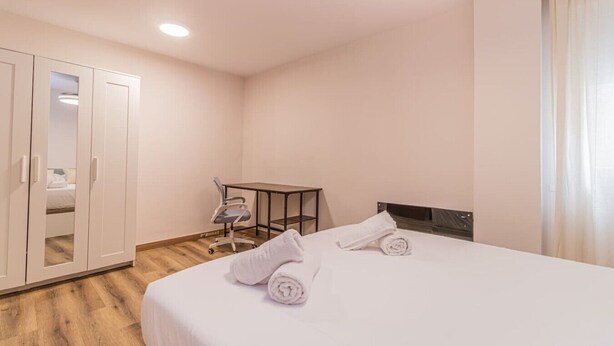 Ein Hotelzimmer mit Bett, Schreibtisch, Stuhl und Kleiderschrank.