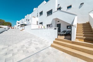 A modern building with a white facade, a staircase leading to a lounge area, and a clear sky. - Casa de Adamant - Ground floor resort apartment with BBQ, shared jacuzzi and pool by OYOOSTAYS (Torrevieja)