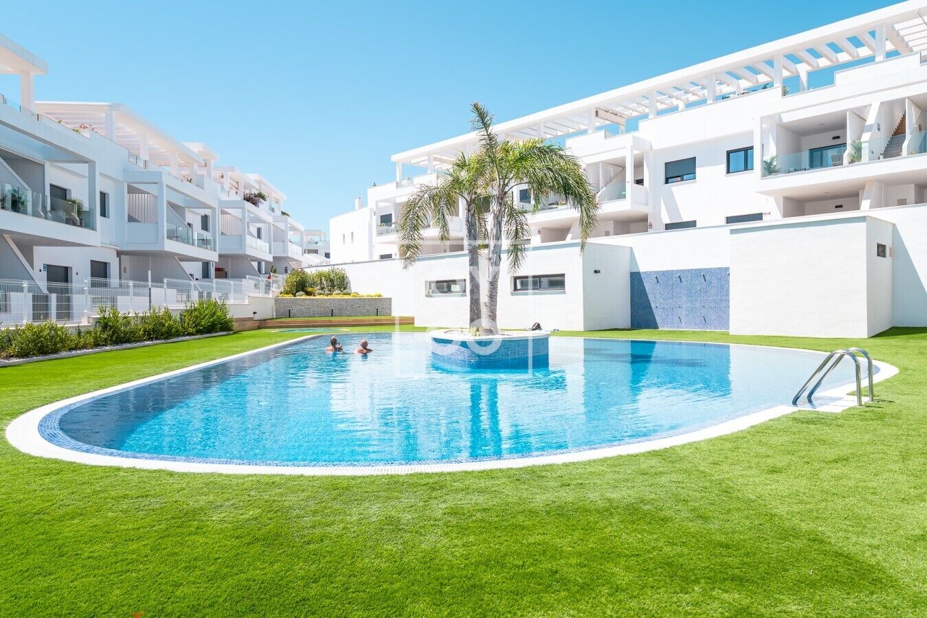 A modern residential building with a swimming pool surrounded by well-maintained grass.