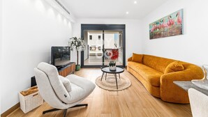 Una sala de estar moderna con un sofá, una silla, un televisor y un cuadro en la pared.