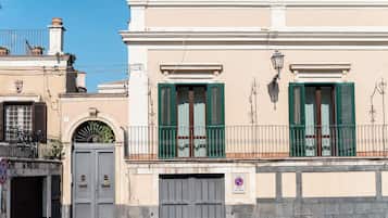 A building with a gated entrance, a balcony with green shutters, and a no parking sign.