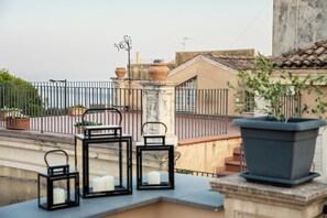 Une terrasse sur le toit, aménagée avec du mobilier d’extérieur, des plantes en pot et offrant une vue sur le paysage urbain.