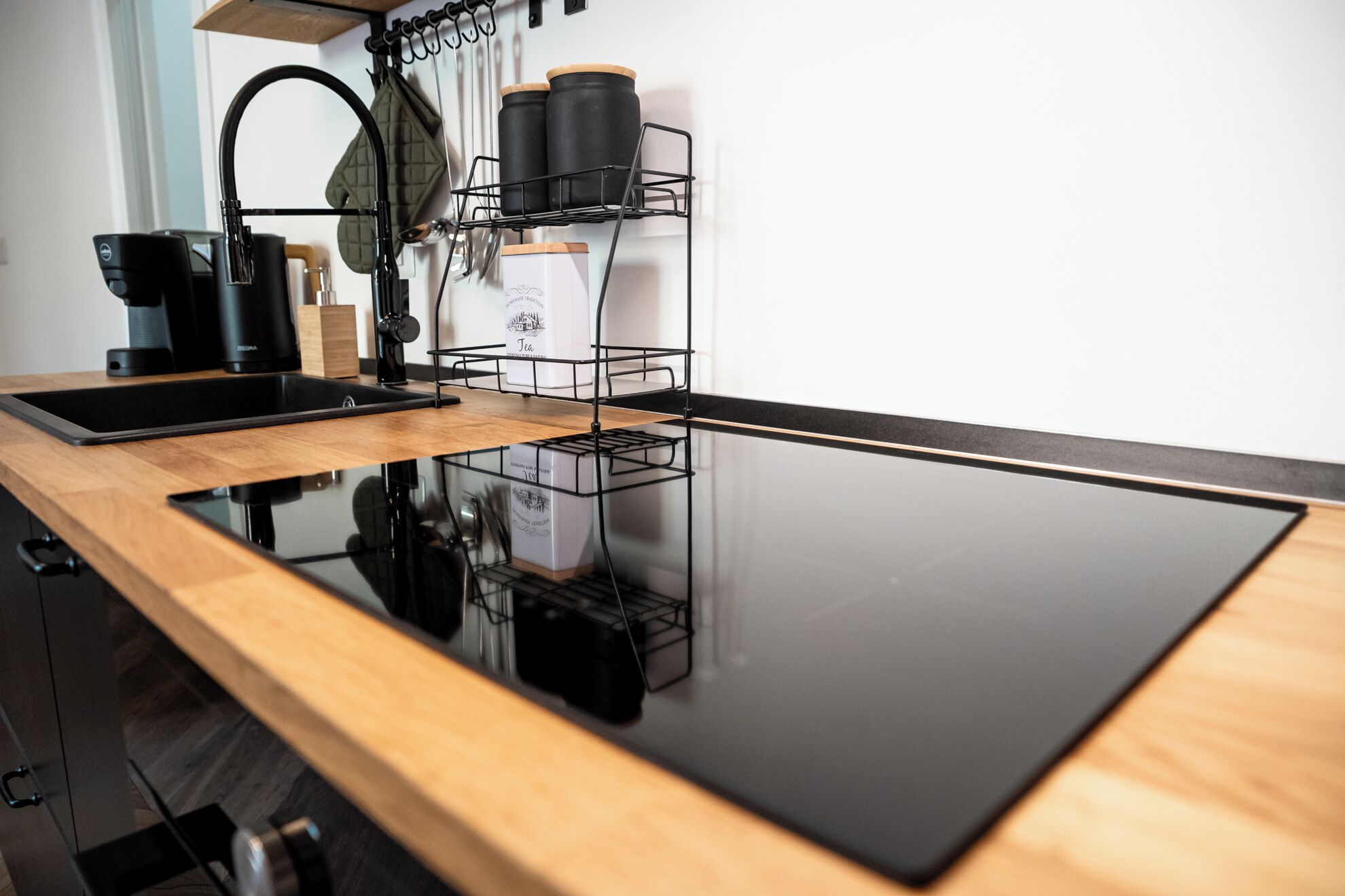 Una cucina con un piano di lavoro nero, una macchina da caffè e un bollitore su uno scaffale.