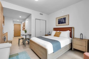 A hotel room with a bed, bedside tables, a desk, and a chair. - Luxury Studio | Pool, Gym & Prime Location (Miami)