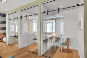 A modern office space with glass partitions, a wooden floor, and a dining area with a table and chairs. - Luxury Studio | Pool, Gym & Prime Location (Miami)