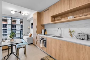 A modern kitchen with wooden cabinets, a white countertop, a sink, and a toaster. - Luxury Studio | Pool, Gym & Prime Location (Miami)