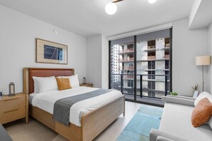 A modern hotel room with a large bed, bedside tables, a desk, and a view of a building under construction. - Luxury Studio | Pool, Gym & Prime Location (Miami)