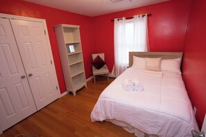 A bedroom with a bed, a wardrobe, a shelf unit, and a chair. - 3-bedroom apartment in serene Elizabeth with cool AC (Elizabeth)