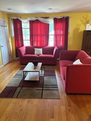 Ein Wohnzimmer mit zwei roten Sofas, einem Couchtisch und Holzboden.