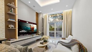 Ein modernes Wohnzimmer mit Flachbildfernseher, einer Couch, einem Couchtisch und einem Bücherregal.