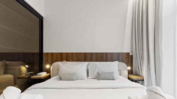 Ein Hotelzimmer mit einem großen Bett, zwei Nachttischen und Blick ins Freie.