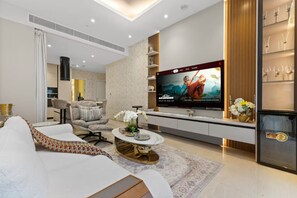Ein modernes Wohnzimmer mit Flachbildfernseher, einer Couch, einem Couchtisch und einer dekorativen Vase.