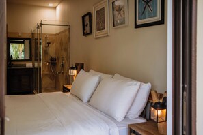 A hotel room with a bed, a shower, and a nightstand with a lamp.