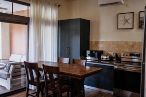 A modern kitchen with a dining table and chairs, a built-in oven, microwave, and a coffee maker. - A gorgeous 2-bedroom, 2-bath apartment in the center of Playa Venao (Las Escobas del Venado)