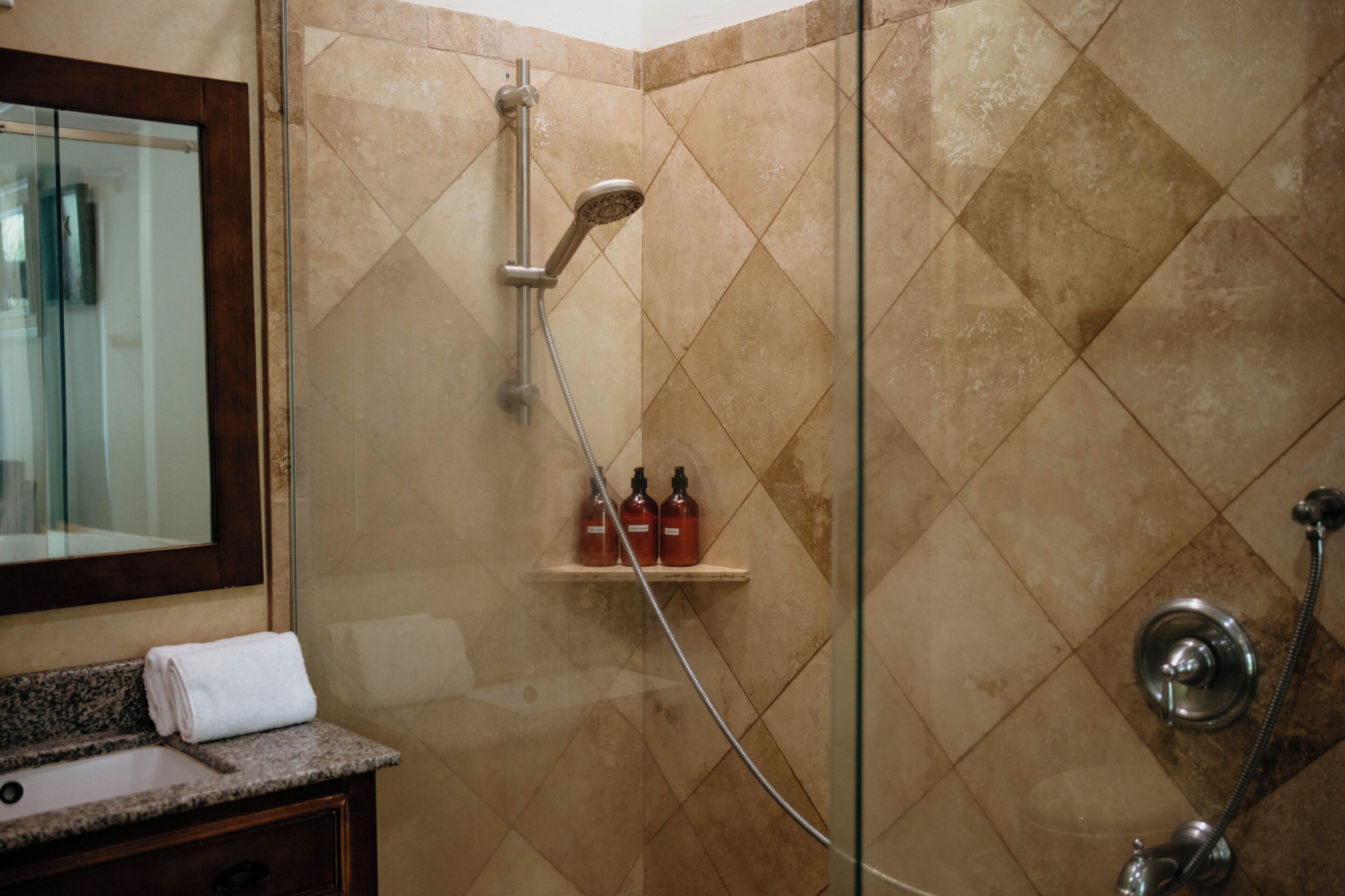 Baño con ducha, lavamanos y espejo.