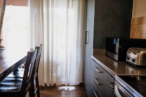 A kitchen with a wooden table, chairs, a microwave, and a toaster.
