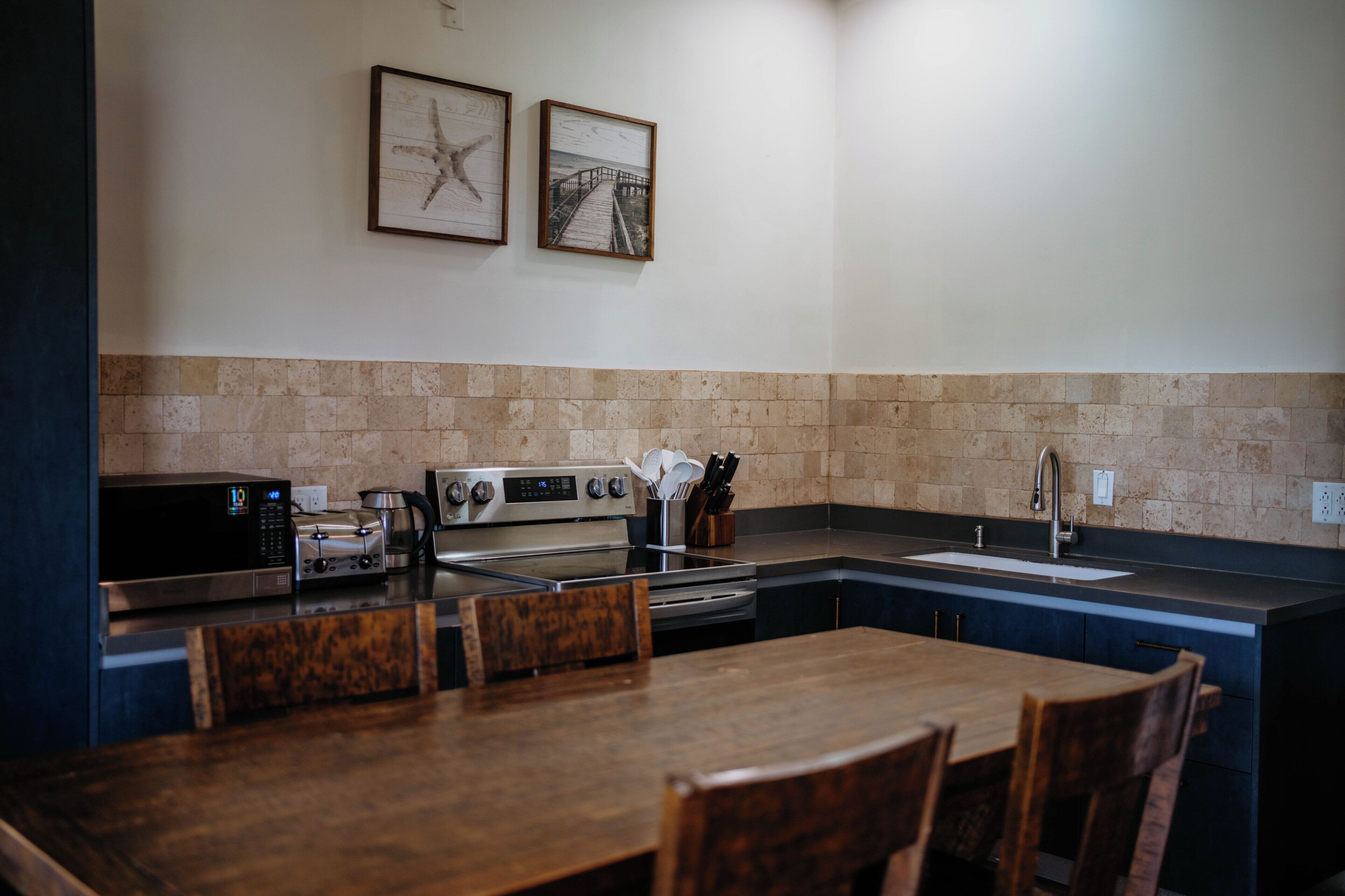 Una cocina con comedor, que incluye estufa, microondas y pileta.