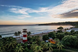 A coastal landscape with a lighthouse, beach, and lush greenery.