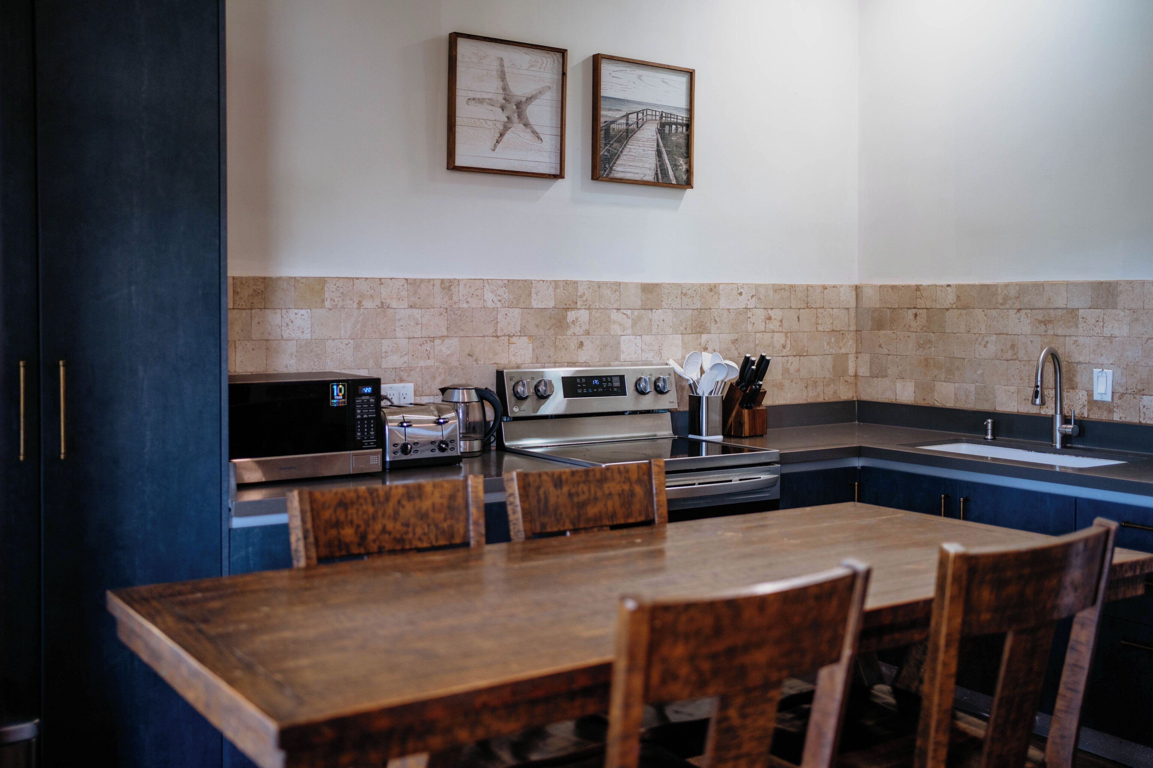 A kitchen with a dining table, chairs, a microwave, a toaster, a stove, and a sink.