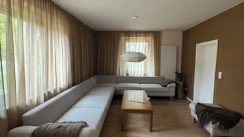 Ein modernes Wohnzimmer mit einer Eckcouch, einem Holztisch und einem kleinen Beistelltisch.