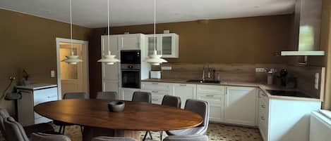 A dining area with a wooden table and chairs, a kitchen with white cabinets, and a patterned floor.